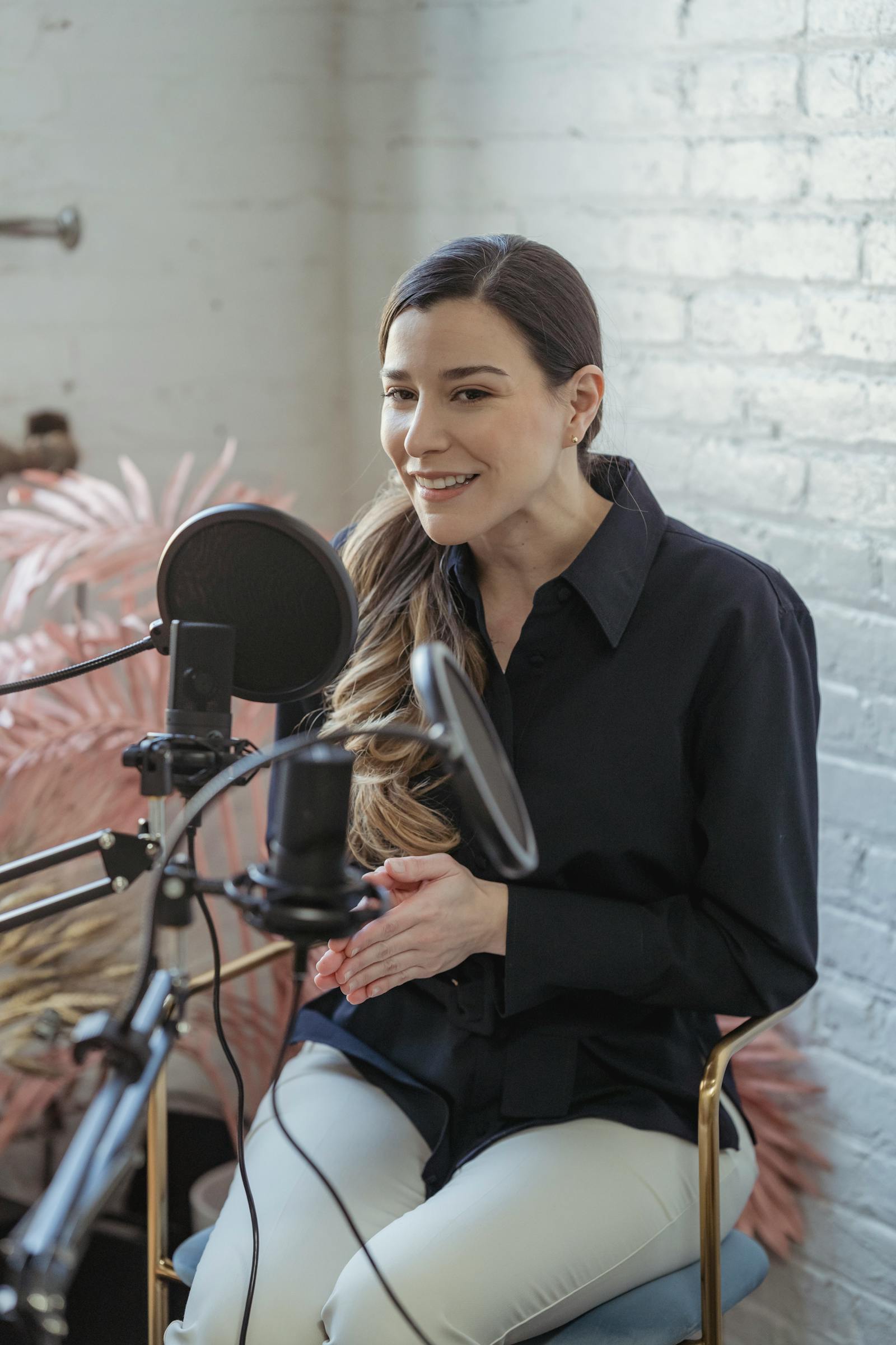 A practitioner recording a podcast — engaged, microphone in foreground, warm wall behind her
